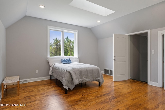 bedroom featuring vaulted ceiling, a skylight, baseboards, recessed lighting, and wood finished floors