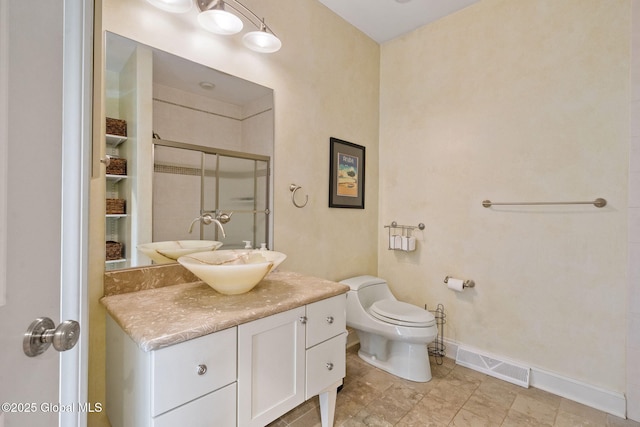 full bath featuring a shower stall, vanity, toilet, and baseboards