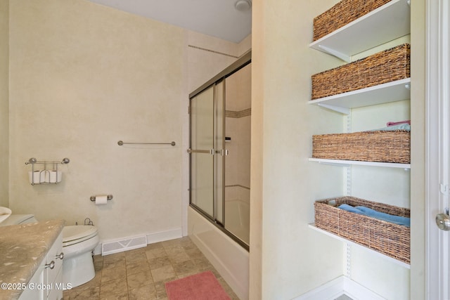 bathroom with toilet, baseboards, enclosed tub / shower combo, and vanity