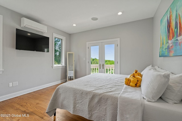 bedroom with a wall unit AC, access to exterior, french doors, wood finished floors, and baseboards