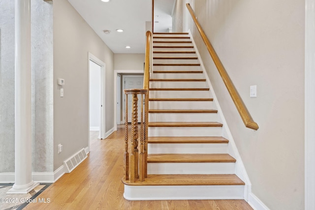stairway featuring wood finished floors, baseboards, recessed lighting, and decorative columns