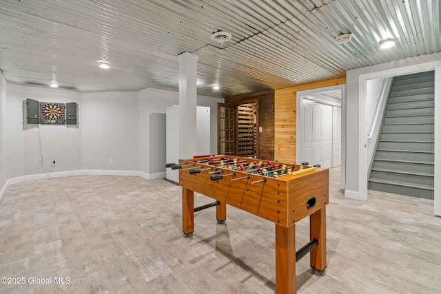 recreation room featuring baseboards, wooden walls, light wood-type flooring, and electric panel