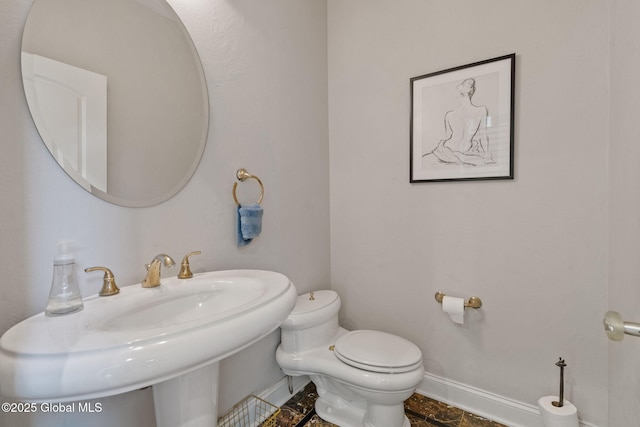bathroom with toilet, baseboards, and a sink