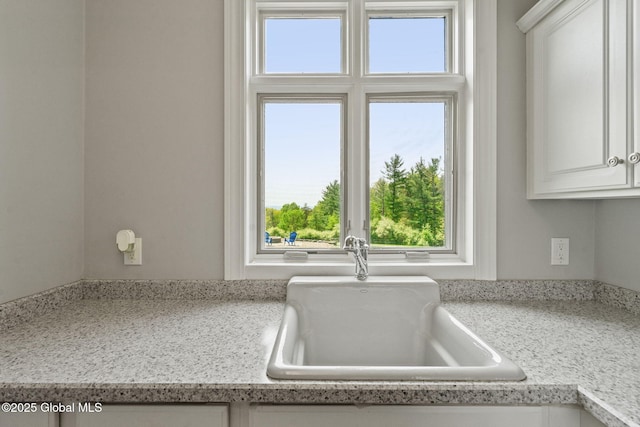 kitchen view of a sink and white cabinetry