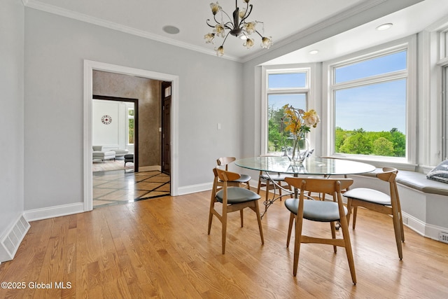 dining space with crown molding, plenty of natural light, a chandelier, baseboards, and light wood-type flooring