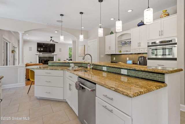 kitchen with stainless steel appliances, a sink, ornate columns, a ceiling fan, and tasteful backsplash