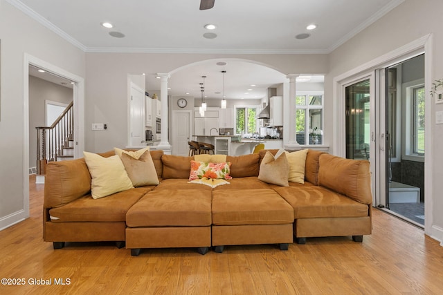 living area with ornate columns, light wood-style floors, plenty of natural light, ornamental molding, and recessed lighting