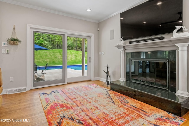 living area featuring wood finished floors, ornamental molding, baseboards, a tile fireplace, and recessed lighting