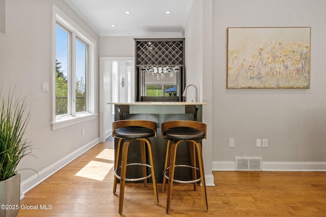 indoor bar with crown molding, wood finished floors, baseboards, and recessed lighting