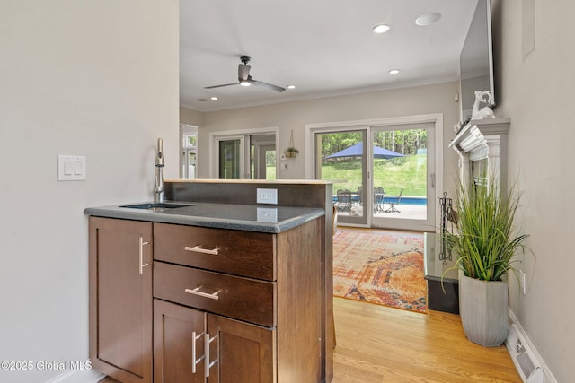 kitchen featuring a sink, crown molding, a ceiling fan, a peninsula, and light wood-style flooring
