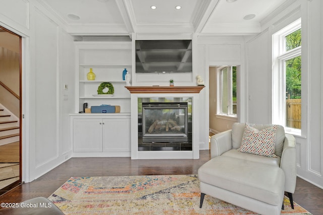 living area with ornamental molding, built in features, stairway, beam ceiling, and a decorative wall