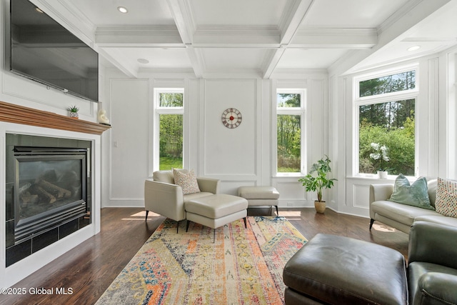 living room with dark wood-style floors, a decorative wall, a fireplace, beam ceiling, and ornamental molding