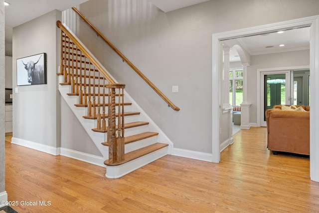 stairs with wood finished floors, baseboards, decorative columns, crown molding, and recessed lighting