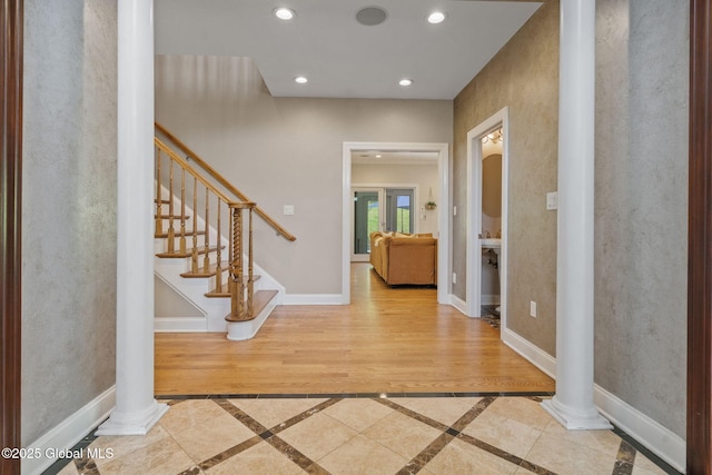entryway with ornate columns, inlaid floor details, recessed lighting, and stairway