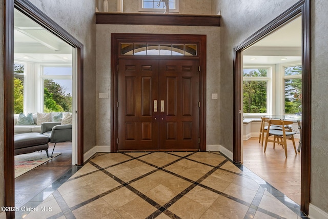entrance foyer featuring healthy amount of natural light, inlaid floor details, baseboards, and a textured wall