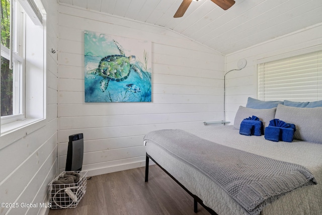 bedroom with wood finished floors, lofted ceiling, wooden walls, and ceiling fan