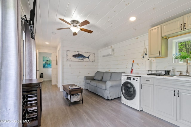 living room with washer / dryer, ceiling fan, wood ceiling, an AC wall unit, and light wood-style floors