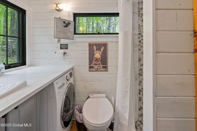 full bathroom featuring plenty of natural light, wooden walls, washer / dryer, vanity, and toilet