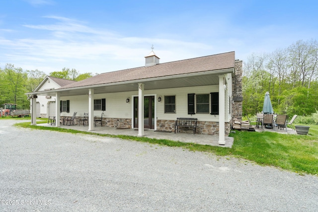 back of house featuring stone siding, a chimney, and a patio area