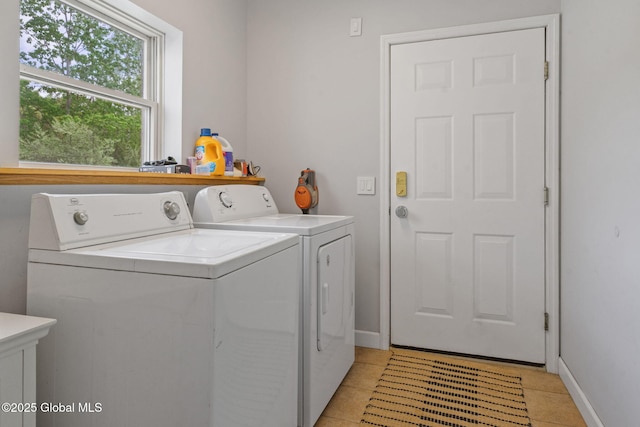 laundry area featuring washer and dryer, light tile patterned floors, and baseboards