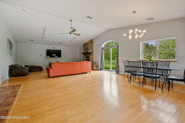 living room with a ceiling fan, wood finished floors, vaulted ceiling, a chandelier, and baseboards