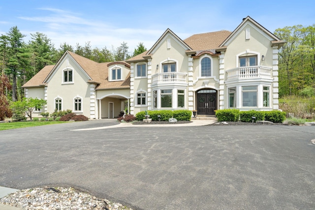 view of front of house with a balcony, french doors, and stucco siding