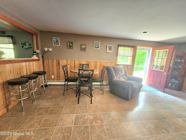 dining area featuring wood walls, a wainscoted wall, and a baseboard heating unit