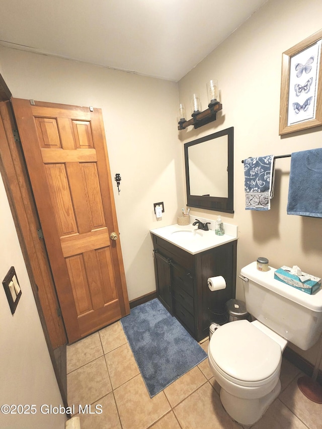 bathroom with toilet, vanity, and tile patterned flooring