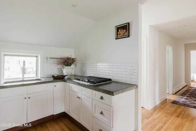 632 Albany Tpke, Chatham, NY 12136 - kitchen featuring a baseboard radiator, wood finished floors, tasteful backsplash, stainless steel gas cooktop, and white cabinetry