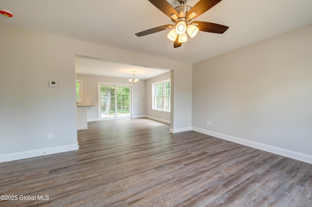 unfurnished room with a chandelier, dark wood-style floors, baseboards, and ceiling fan