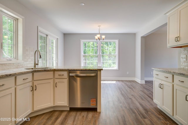 kitchen featuring stainless steel dishwasher, a sink, tasteful backsplash, dark wood-type flooring, and a chandelier
