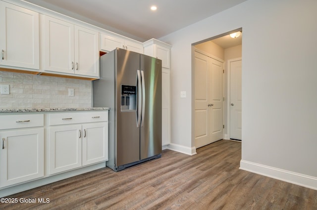 kitchen featuring stainless steel refrigerator with ice dispenser, wood finished floors, backsplash, white cabinetry, and baseboards