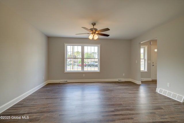 unfurnished room with a ceiling fan, baseboards, and dark wood-style floors