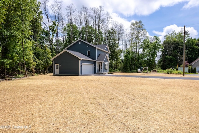 view of front of property with view of scattered trees and asphalt driveway