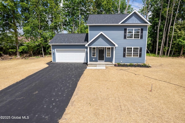 traditional-style home featuring a garage, driveway, and roof with shingles
