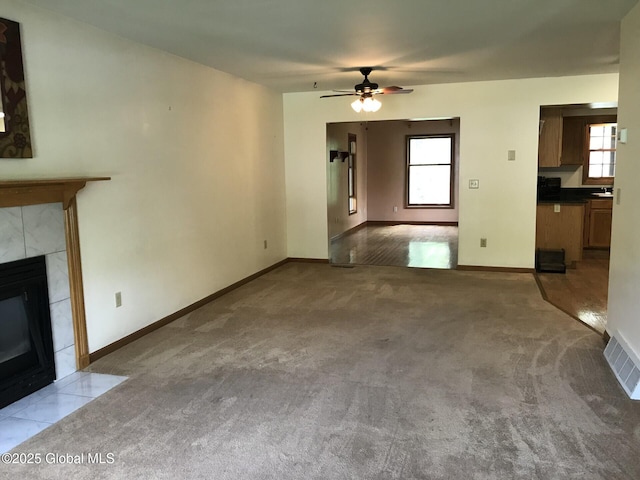 24 Fairmount Dr, Wilton, NY 12831 - unfurnished living room featuring a tile fireplace, carpet flooring, baseboards, and a ceiling fan