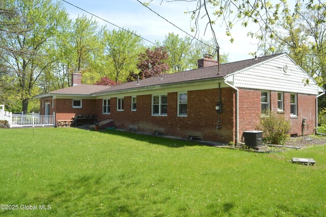 back of house with a chimney, a yard, and brick siding