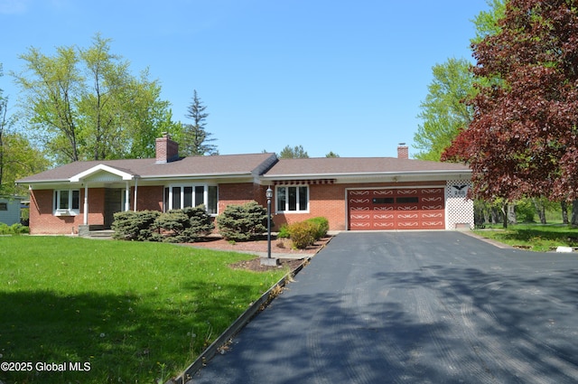 ranch-style home featuring a garage, a chimney, brick siding, and a front lawn