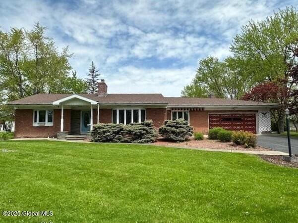 single story home with a garage, a front lawn, a chimney, and asphalt driveway