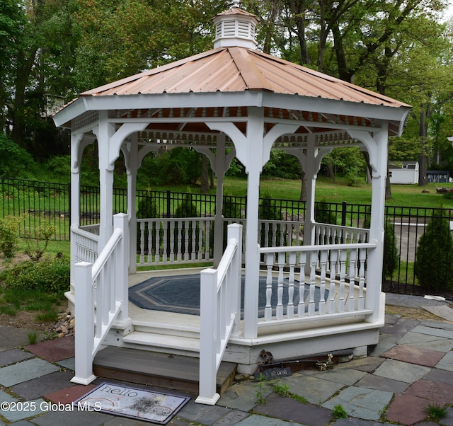 deck with a gazebo, fence, and view of wooded area