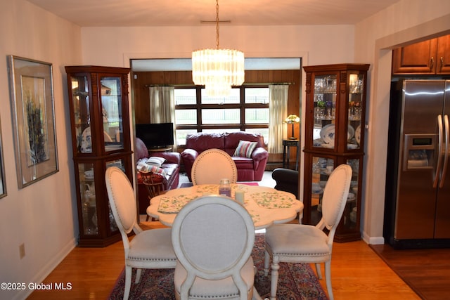 dining area with a chandelier, light wood-style floors, and baseboards