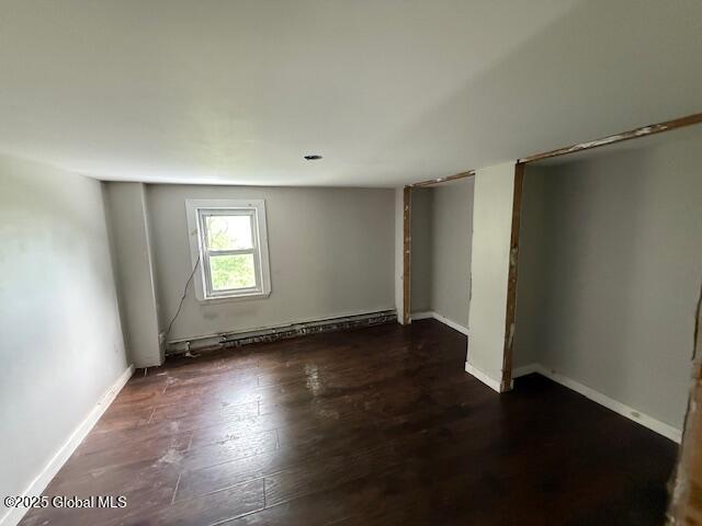 153 River St, Queensbury, NY 12845 - unfurnished bedroom featuring a baseboard heating unit, wood finished floors, and baseboards