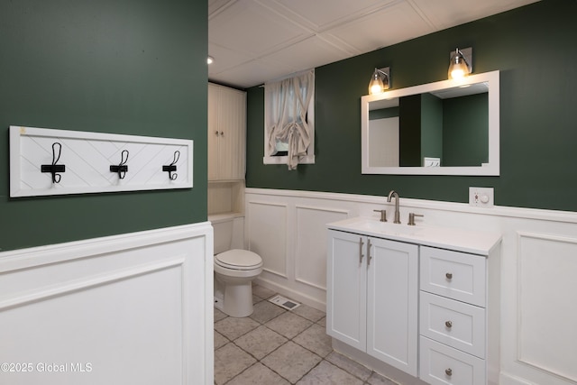 185 Bay St, Glens Falls, NY 12801 - bathroom with tile patterned floors, toilet, vanity, wainscoting, and a decorative wall