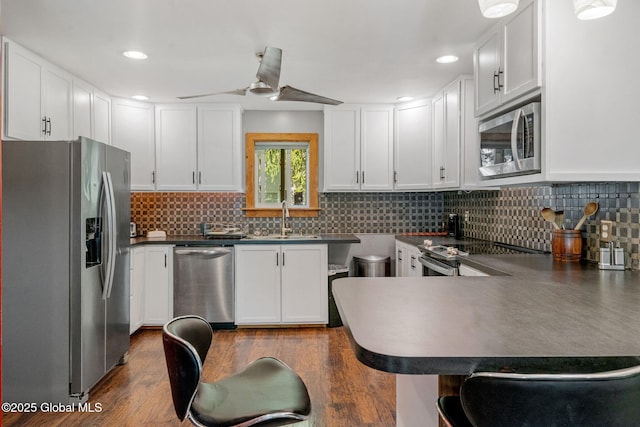 22 Center St, Fort Edward, NY 12828 - kitchen with stainless steel appliances, a sink, dark countertops, a peninsula, and white cabinetry