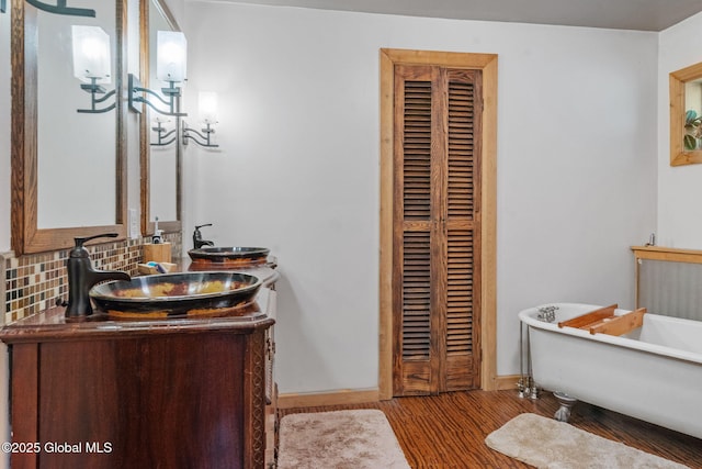 22 Center St, Fort Edward, NY 12828 - full bathroom with baseboards, a freestanding tub, double vanity, wood finished floors, and backsplash