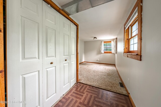 hall with baseboards and dark colored carpet