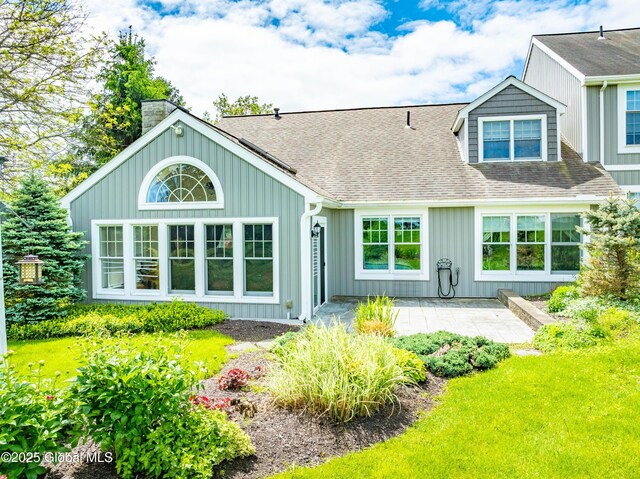 36 Greystone Dr, Guilderland, NY 12186 - back of property with a chimney, board and batten siding, a patio area, a shingled roof, and a lawn