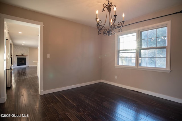 18 Alva St, East Greenbush, NY 12061 - unfurnished room with a chandelier, baseboards, dark wood-style floors, and a brick fireplace