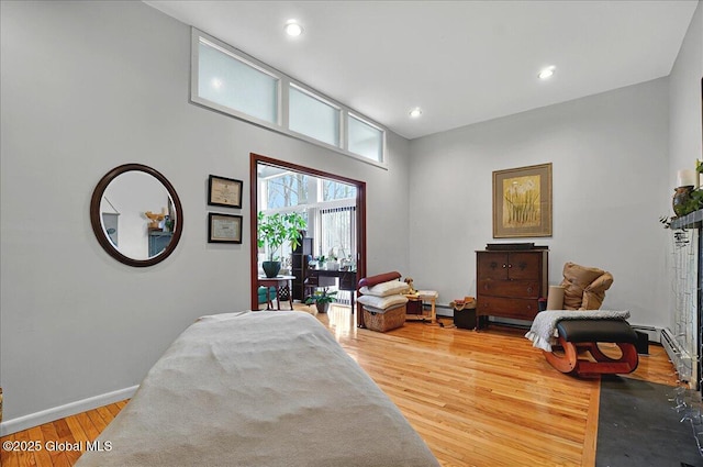bedroom featuring wood finished floors, recessed lighting, baseboards, and a baseboard heating unit
