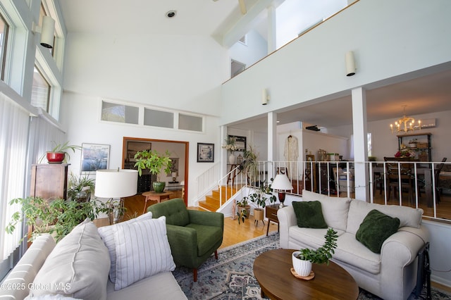 living area with a chandelier, a high ceiling, stairway, and wood finished floors